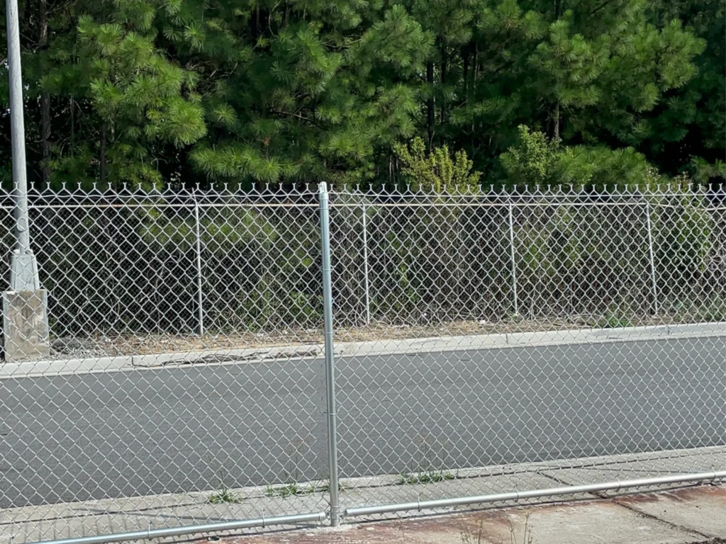 Technicians aligning a commercial fence panel on a Peachtree Corners - GA business perimeter near loading access